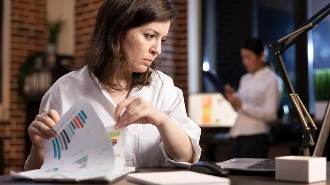 Profissional analisando gráficos relacionados à inflação, juros e impactos econômicos nas empresas em ambiente de escritório.