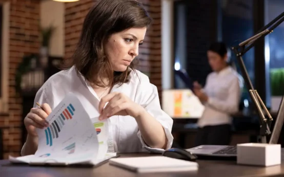 Profissional analisando gráficos relacionados à inflação, juros e impactos econômicos nas empresas em ambiente de escritório.
