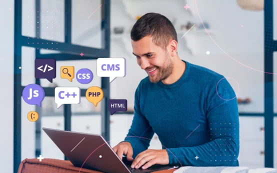 Velocidade do Site: Como o Desempenho Influencia a Experiência do Usuário: Homem programando em um notebook em ambiente de escritório, com ícones de linguagens de programação como HTML, CSS, JavaScript e CMS sobrepostos, representando desenvolvimento de site